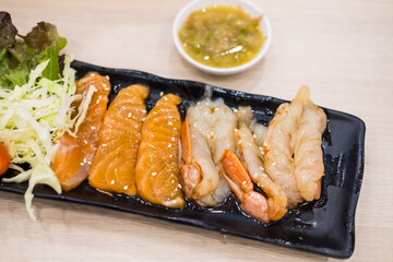 Salmon with shrimp, pickled in Korean sauce, on a black tray