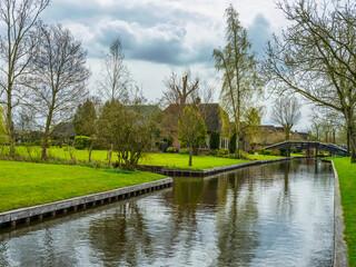 Fototapeta premium Charming village of Giethoorn, Dutch houses and lush gardens on canal bank, Netherlands