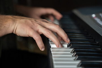 Man hands practice playing synthesizer and improvises upbeat melody. Pianist plays musical...