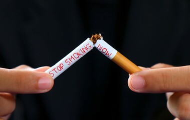 
A man's hand holding a cigarette with the inscription saying stop smoking now ,Under the concept...