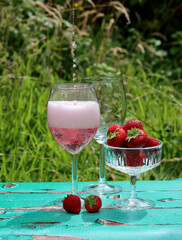 Two glasses of rose sparkling wine and strawberry on a  table. Romantic picnic outdoors. Close up photo of glass tableware. Summer drinks and food. 
