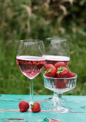 Two glasses of rose sparkling wine and strawberry on a  table. Romantic picnic outdoors. Close up photo of glass tableware. Summer drinks and food. 