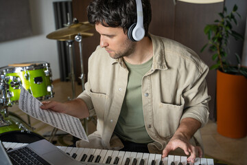 Man gives online synthesizer lesson via laptop showing notes on music sheet. Guy plays notes on...