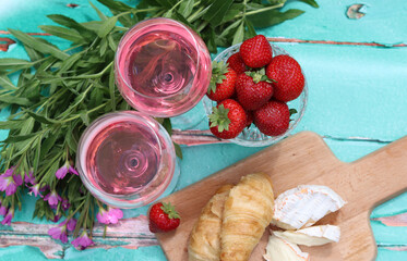 Sunny day in a garden. Fresh fruit, flowers, cheese and wine on a table. Green grass on a background. Blank space for text. 