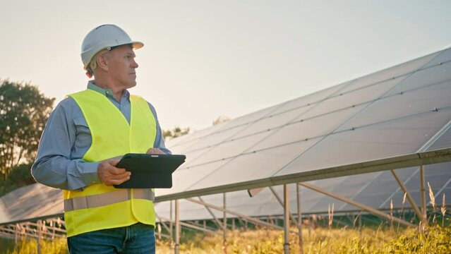 Mature engineer male working alone at professional solar station
