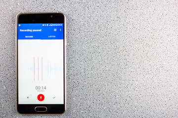 Voice recorder on smartphone screen from above on blue background with copy space. Dictaphone with...