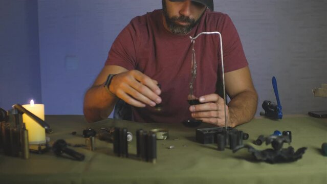 a man doing shotgun cartridges reloading with gun primers, shells, gunpowder, cartridges, scales on the table