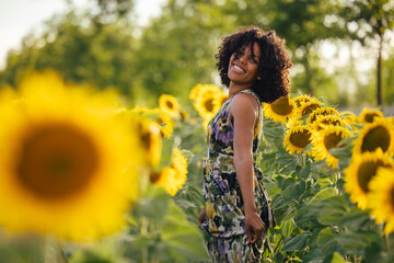Naklejka na ściany i meble Positive woman, wearing a dressed, standing around the sunflower