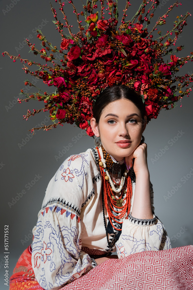 Wall mural portrait of young ukrainian woman in traditional costume and floral red wreath isolated on grey.