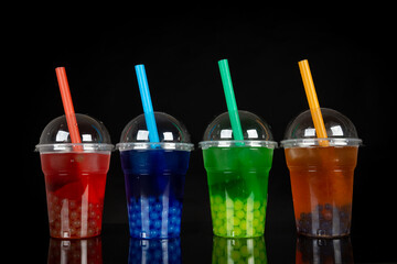 Various Bubble Tea in a plastic cups with drink straws on black background. Take away drinks concept.