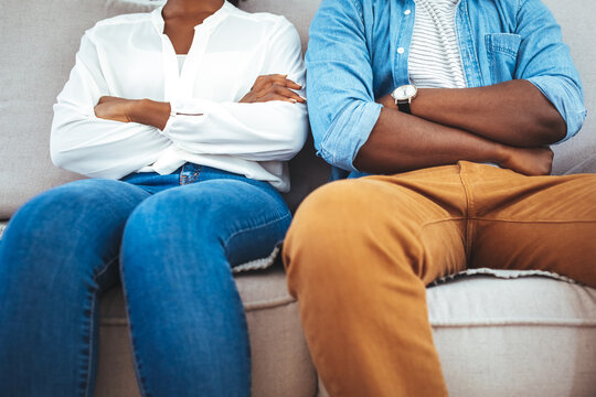 Couple having argument on the couch at home in the living room. Frustrated couple arguing and having marriage problems. Upset couple at home. Sitting on sofa together. Family problems.