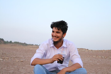 Man enjoying his drink on river side dry land sitting with glass of juice in happy mood summer photography