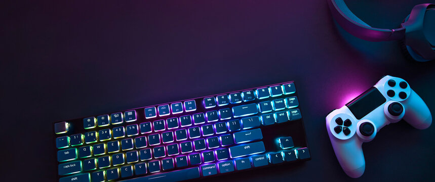 Top down view of colorful illuminated gaming accessories laying on table. Professional computer game playing, esports business and online world concept