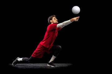 Portrait of young man, volleyball player in motion, training, playing isolated over black studio...