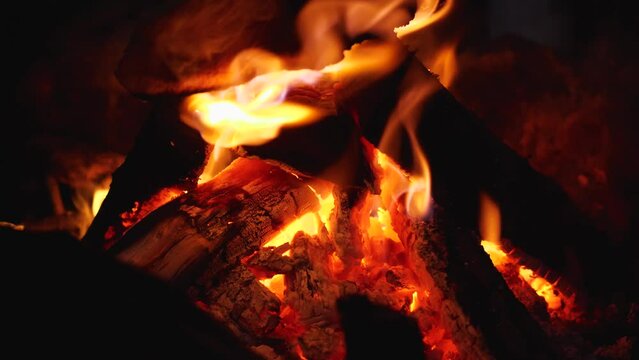 Close-up of a burning fire in the dark. Flames and wood. Red embers, smoke, ash and ash. Camping poster in the mountains