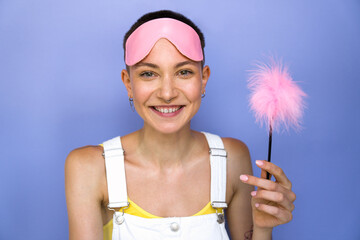 Overjoyed tattooed woman laughing with pink feather stick from sex shop