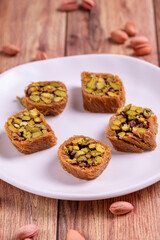 Pistachio kadayif dessert. Kadayif baklava with pistachio filling on a wooden floor. Turkish cuisine desserts. Close-up. local name fıstıklı kadayif