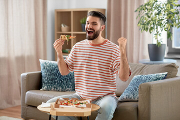 food delivery, consumption and people concept - happy man eating takeaway pizza at home