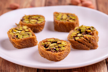 Pistachio kadayif dessert. Kadayif baklava with pistachio filling on a wooden floor. Turkish cuisine desserts. Close-up. local name fıstıklı kadayif