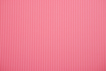 Abstract background made of corrugated paper for pink application. Space for text. Texture. Vertical stripes.