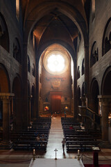 Fototapeta premium The central nave of the Romanesque cathedral. View of the round stained glass window.
