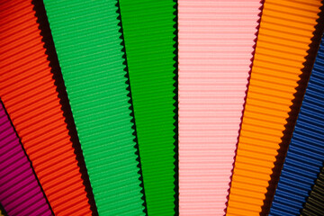 Abstract background made of corrugated paper for application. Space for text. Texture. Sheets of different colors lie in a fan. Green, red, blue, black, pink, orange color.