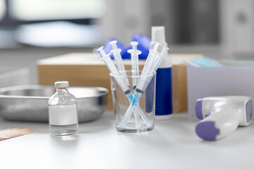 medicine and healthcare concept - close up of syringes, drug in jar and other stuff on table at hospital