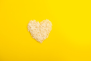 Rice in heart shape on yellow background.
