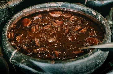 Typical Brazilian feijoada served in clay pot in restaurant