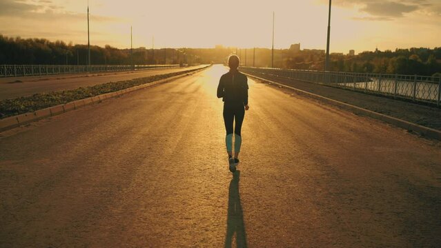amazing slow motion shot with running sportswoman in sunset or sunrise, lady in sportswear is jogging