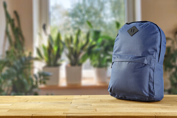 Fototapeta Schoolbag on table and blurred window with green plants.  obraz