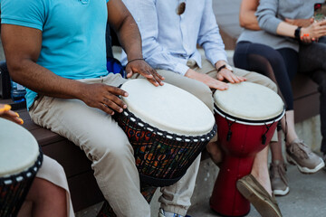 Musicians drum on the street, a large black guy beats the rhythms of Africa on a djemba, pumped muscles, biceps.
