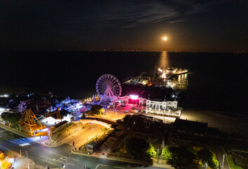 Clacton Pier at night with full moon rising over the sea.