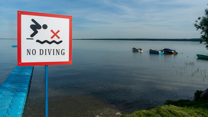 No Diving sign at beach, lake Naroch, Belarus. Warning sign of shallow water. Warning notice sign do not jump in water.