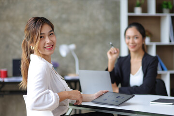 Portrait of a charming Asian businesswoman and her colleagues at an office desk.