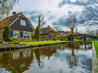Fototapeta na wymiar Beautiful gardens, Dutch houses and bridges over the canal in the Charming village of Giethoorn, Netherlands