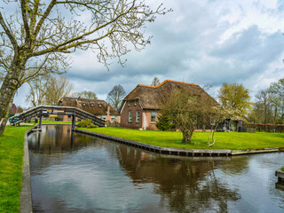Fototapeta na wymiar Islands houses, lush gardens, and bridges of the charming Dutch village of Giethoorn, Netherlands