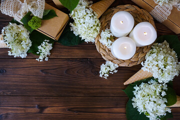 There are lighted candles, gifts and flowers on a dark wooden table

