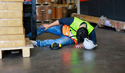 First Aid and safety first concept. Warehouse man worker lying down on floor after accident in warehouse factory. Professional engineering teamwork. Health insurance emergency accident in workplace. - obrazy, fototapety, plakaty
