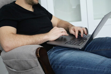 Naklejka premium working at a laptop man white space for work sitting in a chair