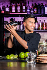 a young barman shaking a cocktail shaker in a pub