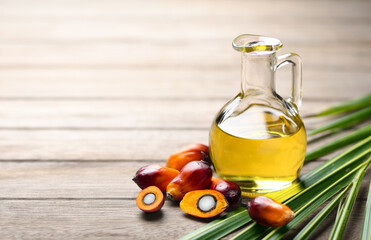 Palm oil with fresh palm nuts on wooden table.
