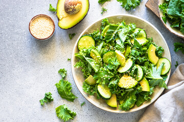 Green salad, vegan meal. Kale salad leaves with cucumber and avocado. Top view.
