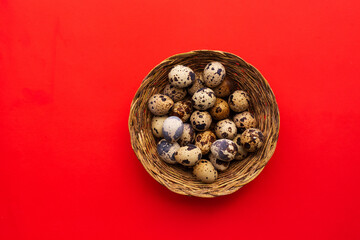 Huevos de codorniz en una bandeja de paja (canasta). Concepto de alimentos. Fondo Rojo.