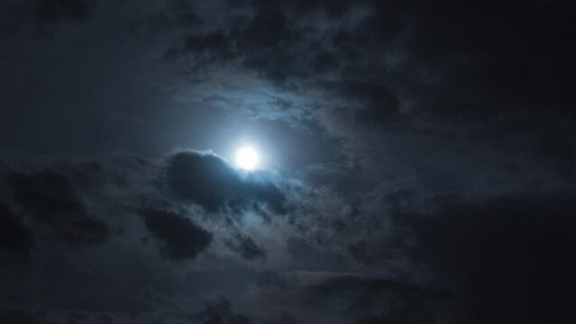 Full moon at night with moving clouds. Night timelapse with clouds and stars floating by