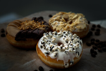 Three doughnuts covered with Cookies and creme, Choco peanut butter and Almendras on wooden cutting board. The concept of delicious glazed donuts, Space for text, Selective Focus.