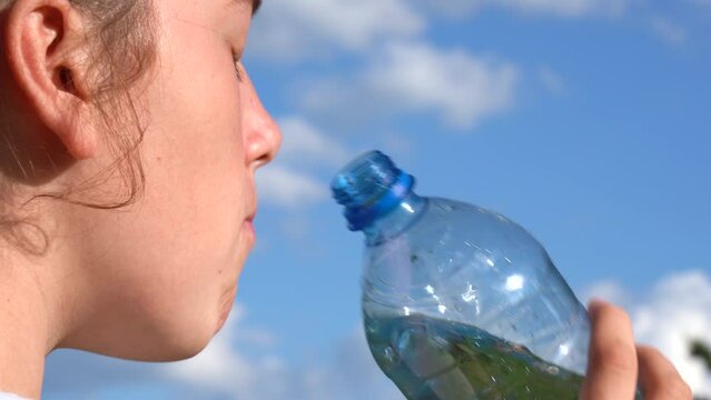 A girl quenches her thirst against a backdrop of sultry clear skies