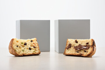 Two slices of chocolate and dried fruit filled panettone, with two gray boxes behind, isolated on...