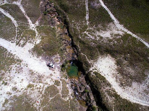 Aerial shot of a river with almost no water and snowy patches on the riverside land