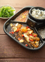 Salmon pickled in soy sauce or shoyu sauce and sprinkled with chili and sliced garlic. with spicy sauce Seaweed and Japanese rice are side dishes on a brown wooden table.